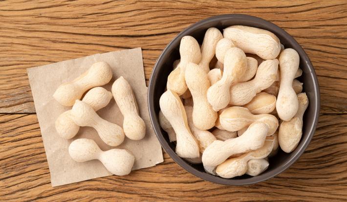 Imagem vista de cima de um bowl escuro com biscoitos de polvilho com um papel ao lado com mais biscoitos em cima.